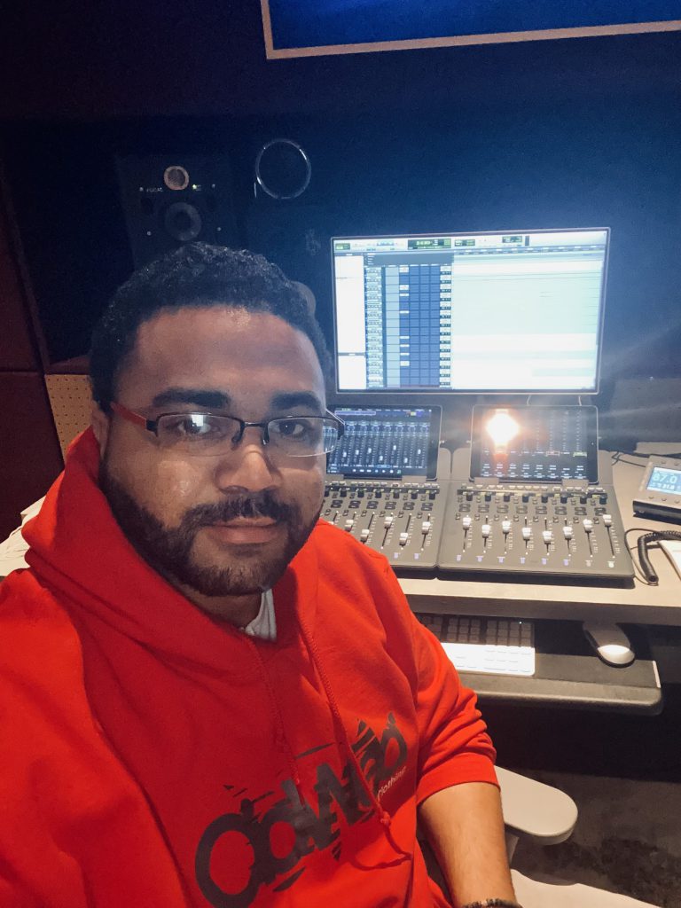 Edilberto posing for a selfie in front of a recording studio console.